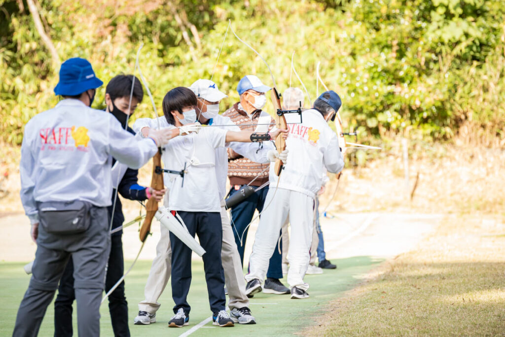 複数人のスタッフがアーチェリーを指導する様子